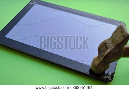 An Old Hammer With A Worn Wooden Handle Hits The Corner Of The Tablet Screen, The Glass Cracks, The 