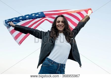 Young Woman Waving American Flag Against The Blue Sky