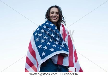 Caucasian Woman Covered With American Flag In Front Of Bluw Sky