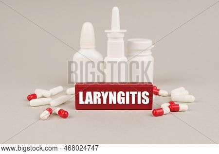 Medical Concept. On A Gray Surface Are Pills, White Jars And A Red Wooden Block With The Inscription