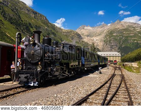 Gletsch, Switzerland - July 15, 2022: A Historic Train With A Steam Locomotive On The Furka Railway 