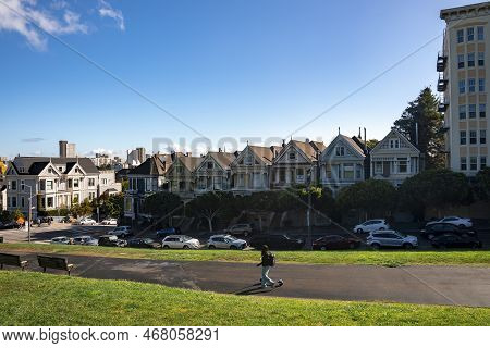Woman Walking On Road In Front Of Painted Ladies Houses At Alamo Square