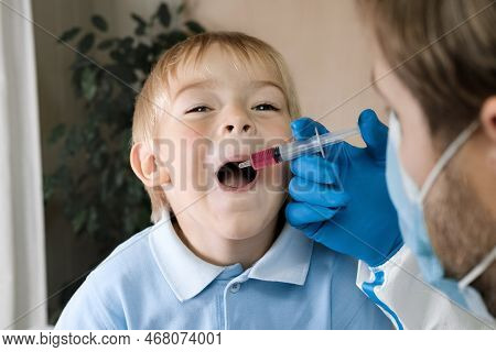 Kid Getting Polio Drops. Doctor Making To Child Oral Vaccination Against Infection. Little Blonde Ha