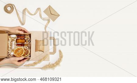 Female Hands Hold Cardboard Gift Box With Self Care Set With Natural Cosmetic On Paper Bag. Packagin