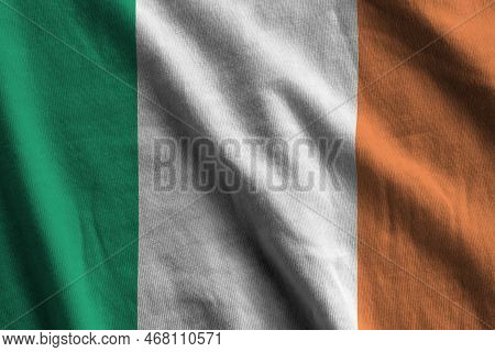 Ireland Flag With Big Folds Waving Close Up Under The Studio Light Indoors. The Official Symbols And