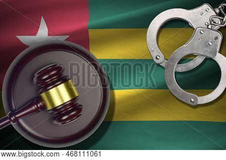 Togo Flag With Judge Mallet And Handcuffs In Dark Room. Concept Of Criminal And Punishment, Backgrou