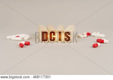 Medical Concept. On A Gray Surface Are Pills And A Red Wooden Block With The Inscription - Dcis
