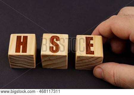 Business Concept. On A Black Surface, A Man Puts Cubes With The Inscription - Hse