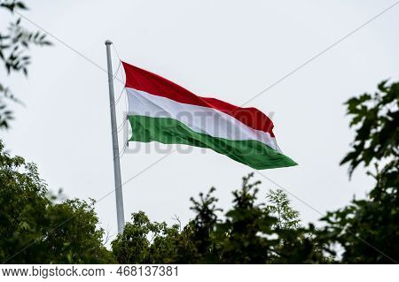 Hungarian Flag Or Flag Of Hungary Waving In The Wind On A Cloudy White Sky Background