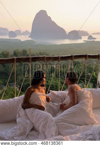 Couple Waking Up In Bed Looking Out Over Ocean During Sunrise At Wooden Hut Moutains Of Thailand