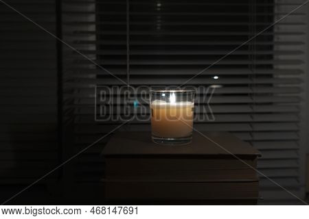 Candle With A Glass Glass Stands In A Dark Empty Room By The Window (close-up). Blackout. Energy Cri