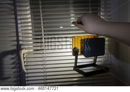 Power Outage Concept. The Girl Holds A Bright Flashlight In Her Hand Against The Background Of A Win