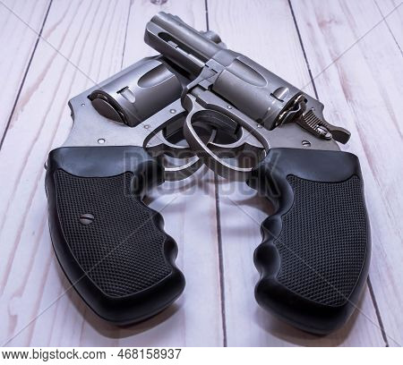 Two Stainless Steel Snub Nose Revolvers, A 357 Magnum And A 44 Special Together On A White Wooden Ba
