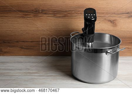 Sous Vide Cooker In Pot On White Wooden Table, Space For Text. Thermal Immersion Circulator
