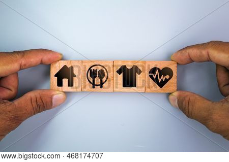 Wooden Cube With Icons Of Food, Clothing, Housing, Medicine, Four Basic Human Needs Concepts. Four B