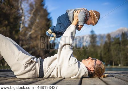 Happy Family. Young Mother Playing With Her Baby Boy Infant Oudoors On Sunny Autumn Day. Portrait Of
