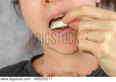 A Woman Puts A Packet Of Swedish Snus Into Her Mouth. Swedish Snus