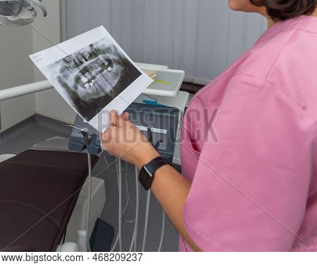 Dentist Woman In Pink Uniform Looking At Roentgen Of Human Jaw.