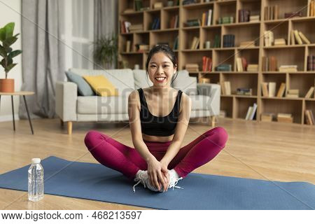 Happy Young Korean Lady Doing Yoga Exercise, Sitting In Baddha Konasana, Bound Angle Or Butterfly Po