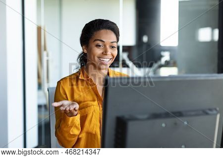 Positive Black Female Entrepreneur Gesticulating At Computer Webcamera, Working And Having Video Cal