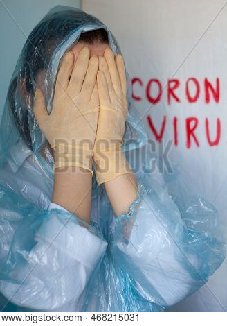 Woman In A Protective Suit Closing Her Face. Inscription Coronavirus In The Background. Coronavirus 
