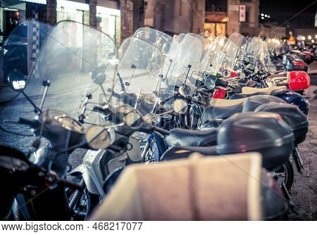 Lucca, Italy - December 2022: Scooter Motorcycles Parked Next To Each Other At Night On A Street Can