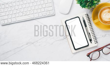 White Office Desk Workspace With Blank Screen Smart Phone, Keyboard Computer, Mouse, Eyeglass, Pen A