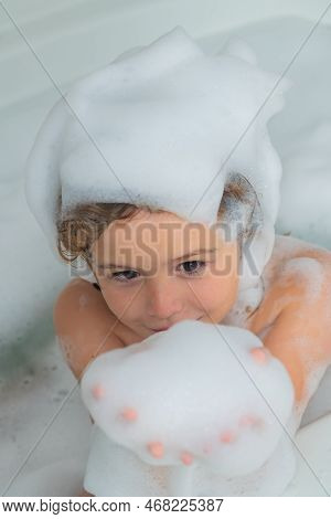 Children Bathing. Child In The Bath With Bubbles. Happy Child Enjoying Bath Time. Little Boy Smiling