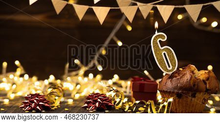 Number 6 Gold Burning Candle In A Cupcake Against Celebration Wooden Background With Lights. Birthda