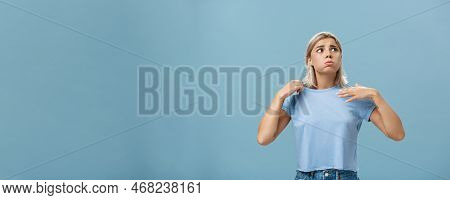 Girl Feeling Discomfort From Heat Standing Over Blue Background In Fug Breathing Out And Frowning Lo