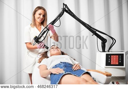 Smiling Woman Lying On Daybed And Receiving Facial Skincare Treatment In Beauty Salon. Female Doctor