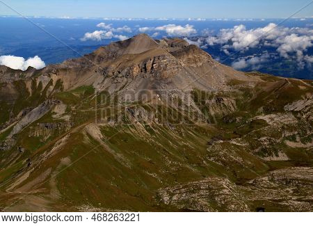 Close-up View Of The Landscape With Mountain Peak In The Foreground Against A Blue Sky With Clouds O