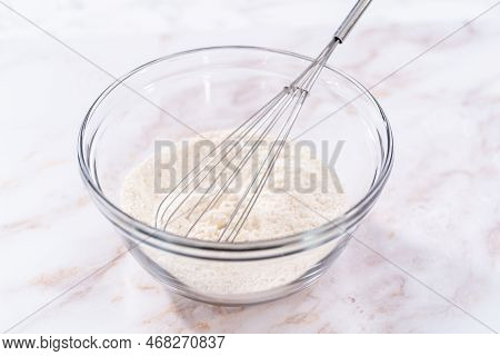 Mixing Ingredients In A Large Glass Mixing Bowl To Bake Apple Sharlotka Muffin.