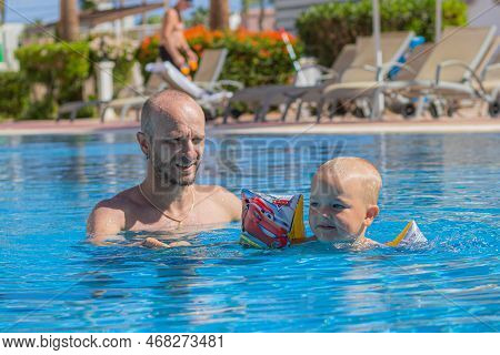 Egypt. Hurghada. 04.14.2021 Father And Child Have Fun In The Pool In Clear Weather. A Father Teaches