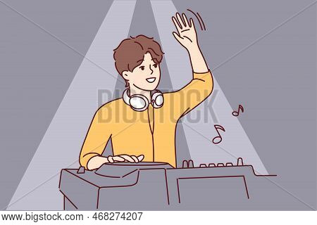 Male Dj Waving To Greet Club Goers And Cheer Up Dancing People. Guy With Headphones Around Neck Stan