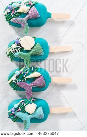 Mermaid Cakesicles With Drizzled Chocolate, Chocolate Mermaid Tails, Seashells, And Sprinkles.