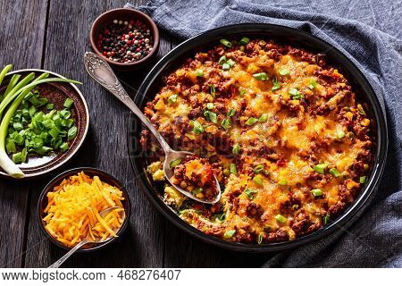 Cajun Beef Cornbread Casserole Topped With Melted Red Cheddar Cheese And Scalions In Baking Dish On 