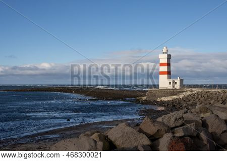 White Lighthouse With Red Stripes On The Coast Of North Atlantic Ocean. Many Seagulls. Waves During 