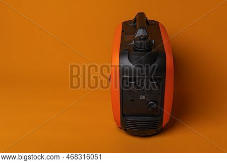 Electricity Generator. Inverter Gasoline Generator On An Orange Background. Studio Shot.