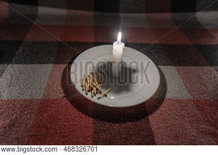 A Handful Of Matches Lie Near A Burning Candle (close-up). Power Outage Concept. Blackout. Energy Cr