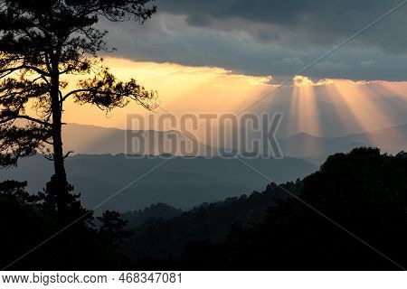 Natural View Of Dramatic Sunset With Godlight Shining Through The Cloudy Sky Over Mountain Ranges In