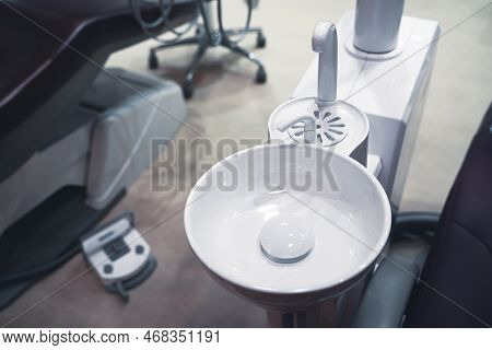 Closeup Top View Of Clear Dental White Ceramic Spit Sink Near Chair In Dentist Office