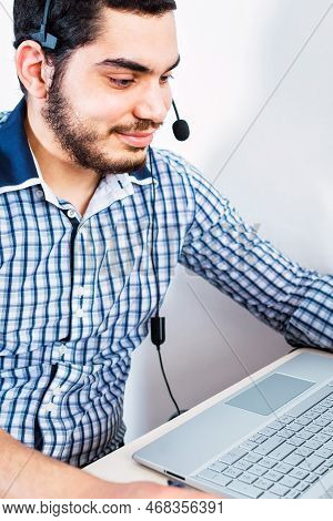 Young Man Sit At Home Office Room Wearing Headset, Using Laptop. Video Call Event With Clients Or Pe