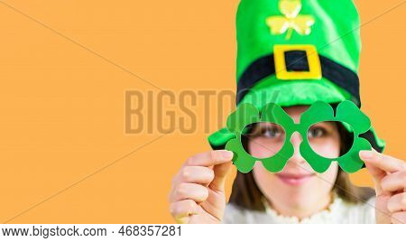 Caucasian Girl In Mask Of Leprechaun Shamrock Clover Glasses For Irish St. Patrick's Day On Orange S