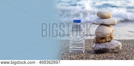 Pebbles In Pyramid One Over Another And Bottle With Drinking Water