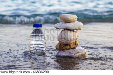 Pebbles In Pyramid One Over Another And Bottle With Drinking Water