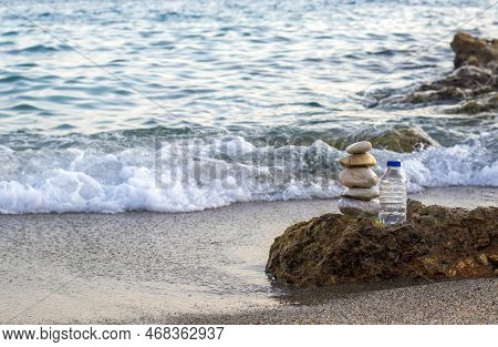 Pebbles In Pyramid One Over Another And Bottle With Drinking Water