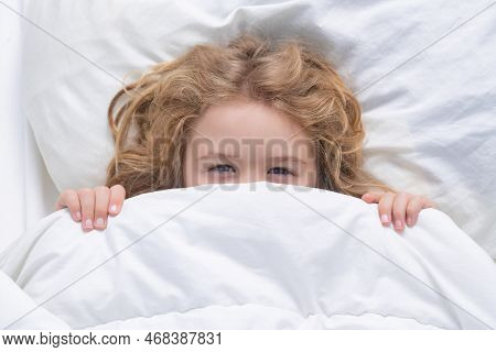 Kid Under Covers, Face Cover With Blanket. Child Wakes Up In The Morning In The Bedroom. Cute Little