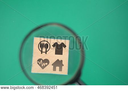 Magnifying Glass Looking For Icons Of Food, Clothing, Housing, Medicine, Four Basic Human Needs Conc