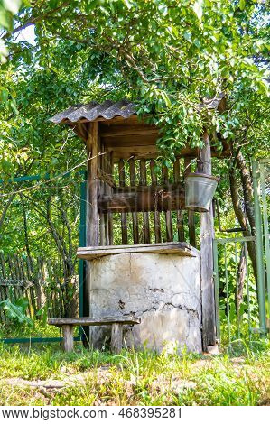 Old Well With Iron Bucket On Long Forged Chain For Clean Drinking Water